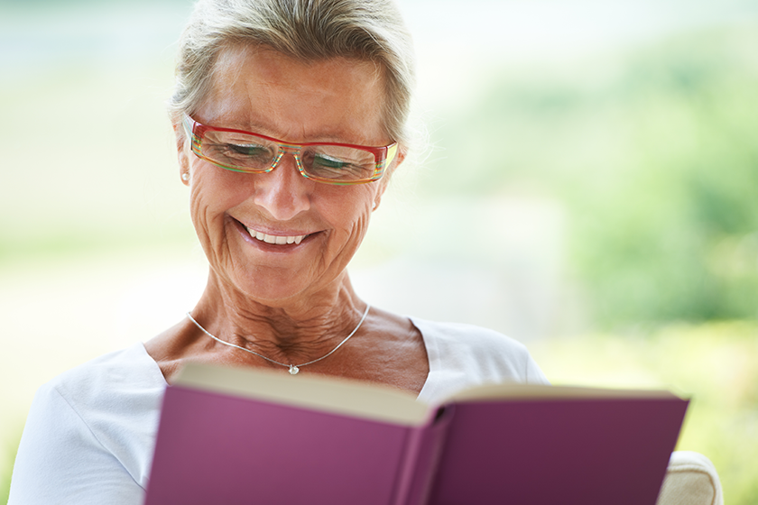 This is such a great story. A delighted woman reading an enjoyable book in her lounge.